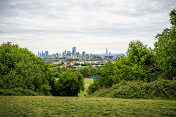 A view across the fields and trees to the City of London from the Parliament Hill Viewpoint in Hampstead Heath, London - obrazy, fototapety, plakaty