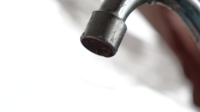 The old tap on the kitchen mixer is leaking. Tap water dripping. Daylight macro photography.