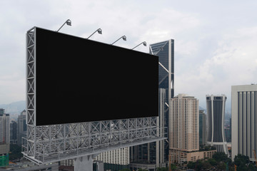 Blank black road billboard with Kuala Lumpur cityscape background at day time. Street advertising poster, mock up, 3D rendering. Side view. The concept of marketing communication.