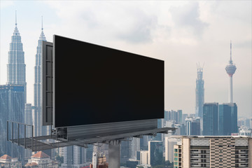 Blank black road billboard with Kuala Lumpur cityscape background at day time. Street advertising poster, mock up, 3D rendering. Side view. The concept of marketing communication.
