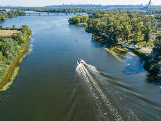 Fototapeta premium Motor boat in the Dnipro river. Sunny clear summer day. Aerial drone view.