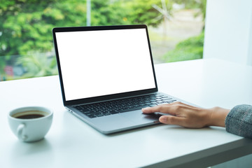 Fototapeta premium Mockup image of a hand using and touching on laptop touchpad with blank white desktop screen in office