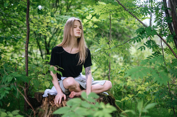 Practice of meditation and interaction with nature. Girl in green forest