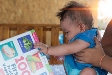 Close up of little baby while the baby learning to reading from mother or looking at the book on the mother's hands (education baby or baby growing up concept) (soft focus)