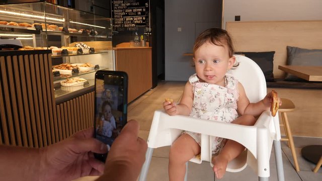 Take smart phone picture of baby eating for addvertising photo of bakery shop in interior child sit in babysit with some cookies