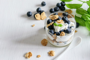 Fresh yogurt, blueberries and granola on the white rustic table. Healthy food, healthy  lifestyle.