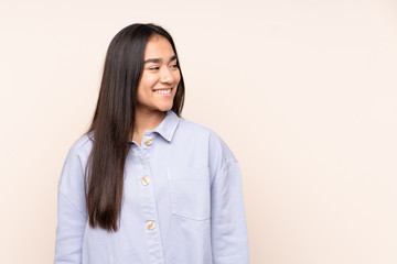 Young Indian woman isolated on beige background looking to the side and smiling