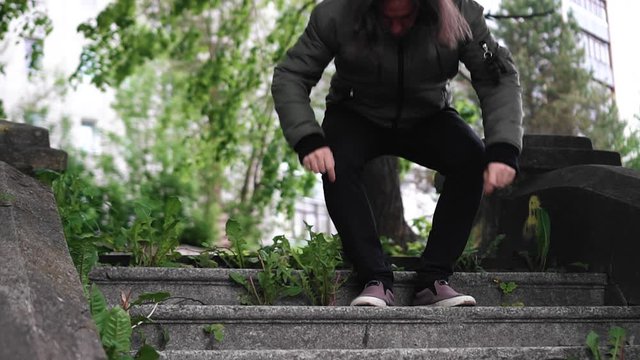 A lonely guy sits on the stone steps and tries to get warm. Front view. A frustrated person. Front view.