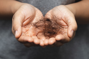 woman slicking hair falling out in two hand after facing hair loss problem of maintenance losing by...
