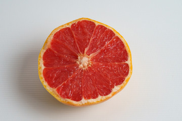 Half a ripe grapefruit on a white plate. Closeup.