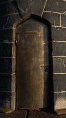 Heavy reinforced steel door at the base of a stone tower
