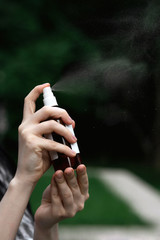 Close-up of female hands with a bottle of spray. Dysenfection, self-care.