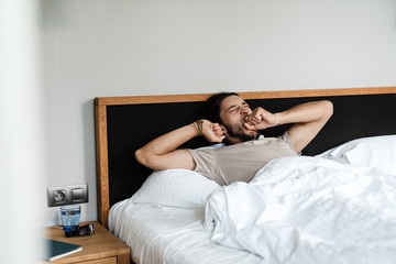 Fototapeta premium Happy young man waking up in the morning in bed