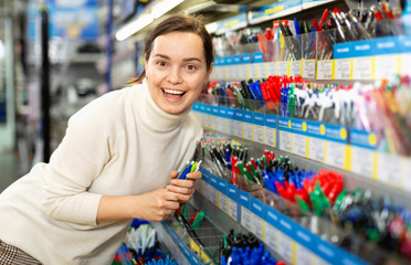 Portrait of happy smiling woman choosing ball pen at stationery store