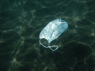 Fototapeta premium Disposable coronavirus face mask floating in the Sea. The Canary Islands. Covid-19 pollution.