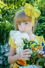 beautiful little girl with long Golden hair and a yellow bow looks at the camera with a smile