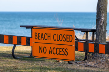 Beach closed no access sign posted with beach and water in background