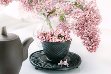 Cup of tea with lilac flowers on a light background. Mocap for postcards. Spring. Vase with lilac. Copy space. concept of holidays and good morning wishes