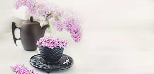 Cup of tea with lilac flowers on a light background. Mocap for postcards. Spring. Vase with lilac. Copy space. concept of holidays and good morning wishes