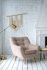 beige armchair in a bright room against a white wall, fireplace