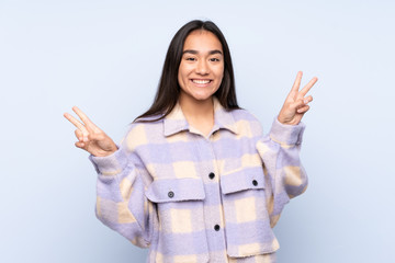 Young Indian woman isolated on blue background showing victory sign with both hands