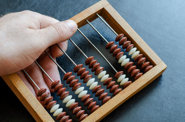A middle aged Caucasian man holds a wooden abacus.