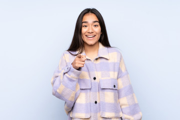 Young Indian woman isolated on blue background surprised and pointing front