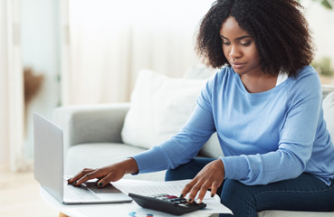 Woman using calculator and pc at home