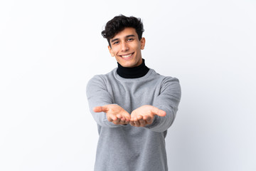 Young Argentinian man over isolated white background holding copyspace imaginary on the palm to...