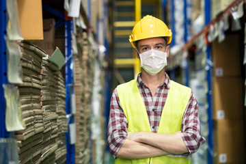 Male engineer worker wear mask work during COVID in warehouse.