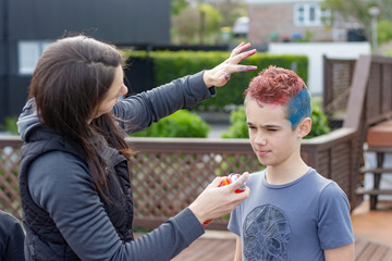 happy family having fun at home. the boy's mother is spraying he's hair with colored dye. 