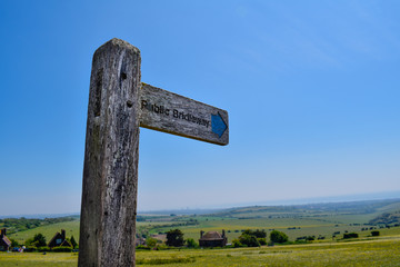 Public Bridleway Footpath Sign in the countryside in a green field with blue sky