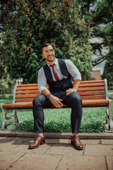 Obraz premium a young sexy businessman in a suit sitting in park on job break