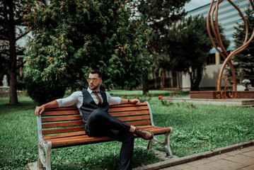 a young sexy businessman in a suit sitting in park on job break