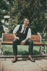 a young sexy businessman in a suit sitting in park on job break