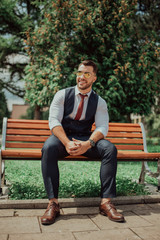 Fototapeta premium a young sexy businessman in a suit sitting in park on job break