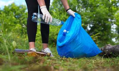 Volunteer collecting bottles in the forest. Environment pollution concept.