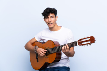Obraz premium Young Argentinian man with guitar over isolated blue background pointing up a great idea