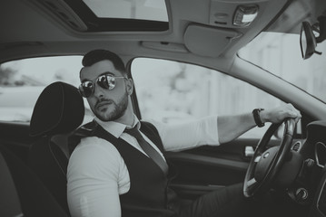 A young businessman in a suit goes to work with car