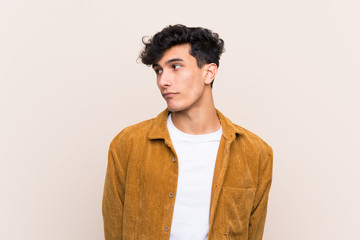 Young Argentinian man over isolated background making doubts gesture looking side