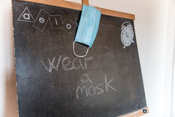 Una pizarra negra con las palabras wear a mask escritas a mano