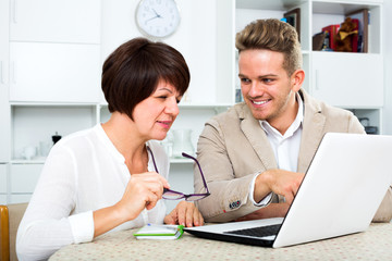 Young man tells his mother about new software and shows his on laptop