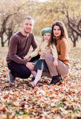 Fototapeta premium Mom, dad and their little daughter are walking in the autumn park.