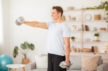 Strength training for arms. Muscular guy raises dumbbells in front of him in interior