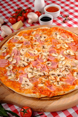 Rustic pizza with cheese, ham, sausage, mushrooms and tomatoes sauce, served on a wooden board for a dinner in italian restaurant background, top view. Classic Italy food. Close up