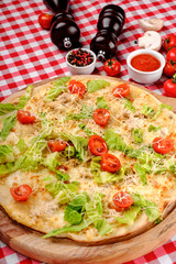 Pizza vegetarian with cherry tomato, lettuce, caesar sauce, pepper, cheese, vegetable and tomatoes sauce, served on a wooden board for a dinner in italian restaurant background, top view.