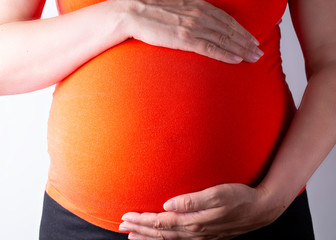 Schwangere Frau hält ihren schwangeren Bauch mit beiden Händen