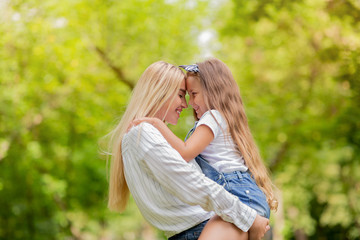 Obraz premium Lovely Mother Embracing Carrying Daughter Spending Weekend In Green Park
