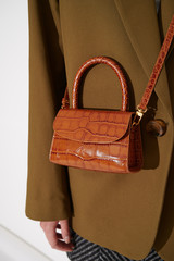 Girl in green jacket with beautiful brown leather handbag. Luxury handmade bag with reptile effect....