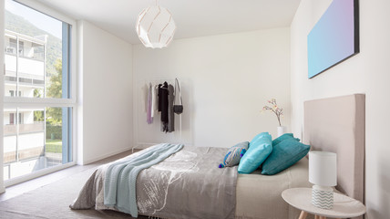 Elegant bedroom with white walls, double bed and lots of pillows